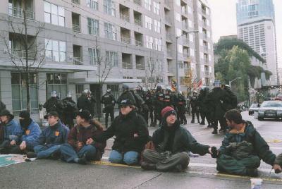 Demonstrators sit down on Pike Street a block from the Seattle Convention Center.
